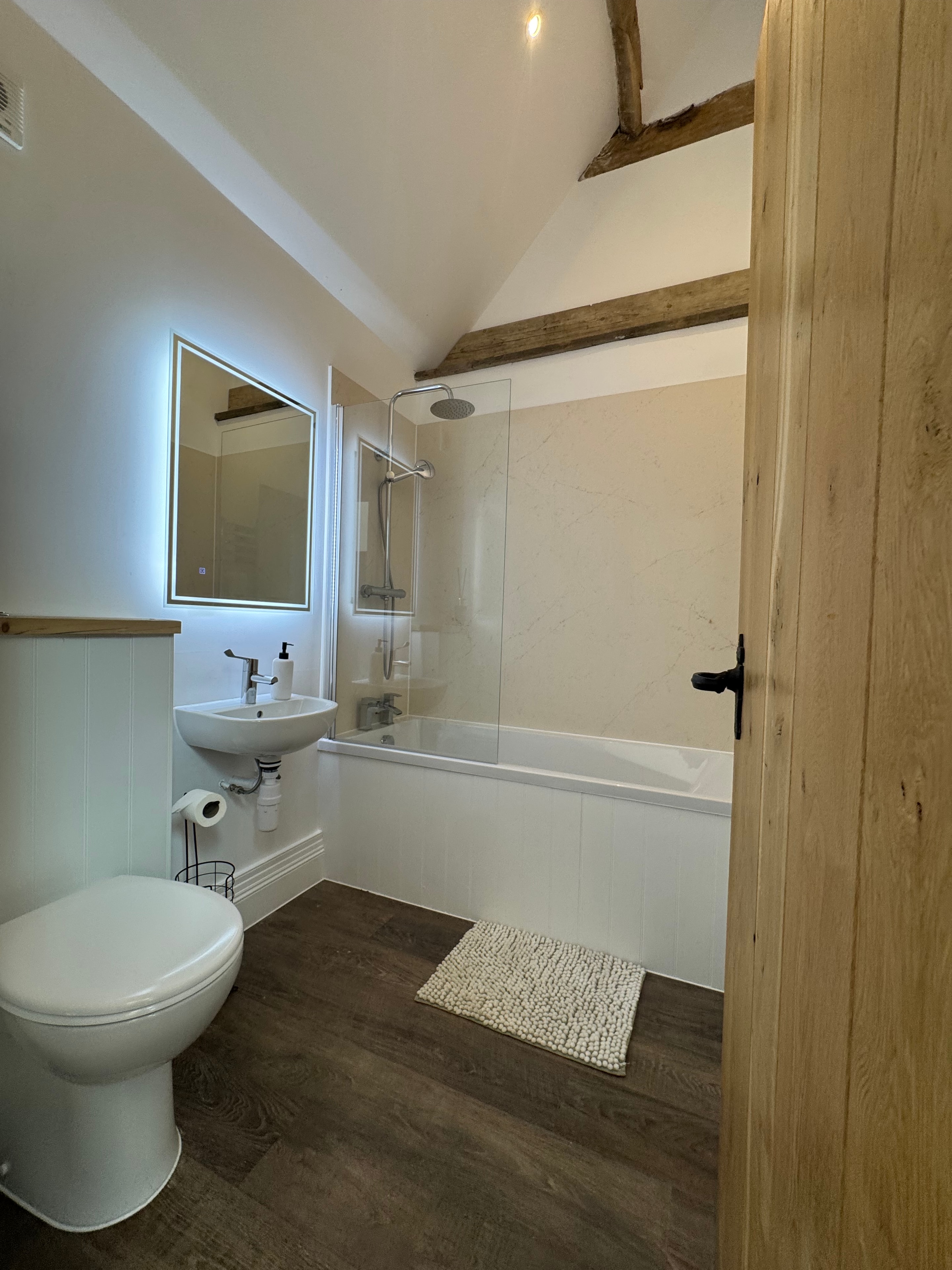 En suite bathroom with marble tiles and oak beams
